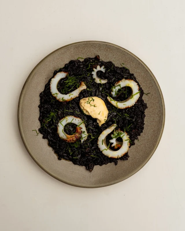 Over in the wine bar: Squid ink rice, grilled cuttlefish, lemon aioli.

Calasparra rice, cooked down in a sofrito and an aromatic fish stock infused with ginger and fennel, gets its deep black colour from squid ink. Topped with cuttlefish from @theseathesea_, a dollop of preserved lemon aioli (thanks to @shrub.london), and a hit of leek top juice—a punchy byproduct of a recent guest chef menu. Low on waste, big on flavour.